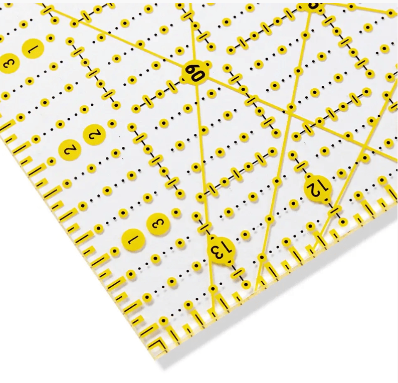 Transparent plastic ruler with yellow grid markings and angle indicators.