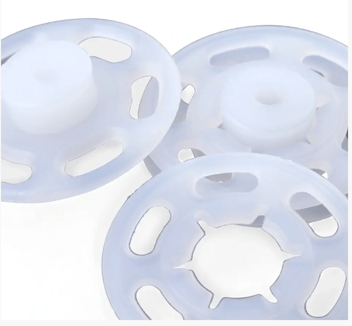 Three white plastic snap fasteners with cutouts.