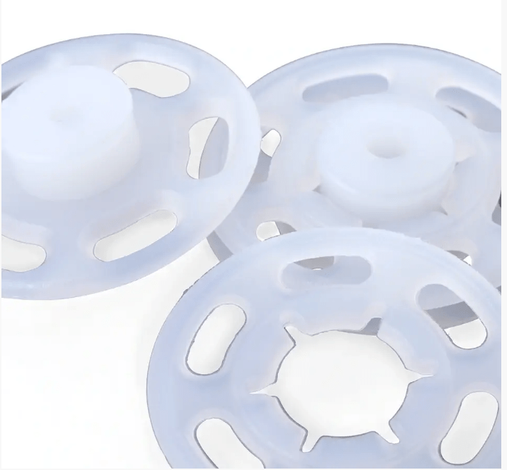 Transparent plastic snap fasteners with slotted edges.