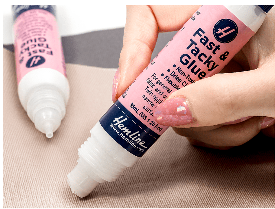 A hand holds a tube of Fast & Tacky Glue with a pink label.