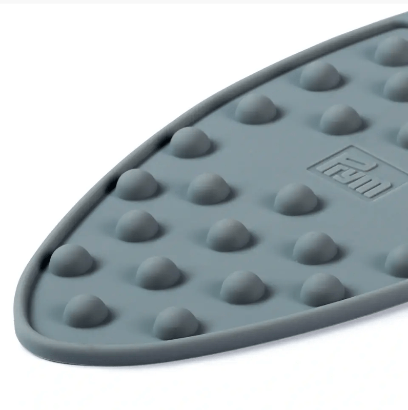 A grey silicone mini iron rest with raised bumps and a logo.