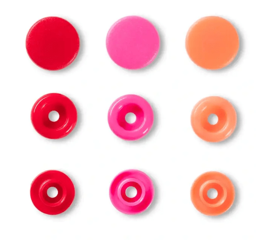 Assorted colorful plastic snap fasteners in red, pink, and orange.