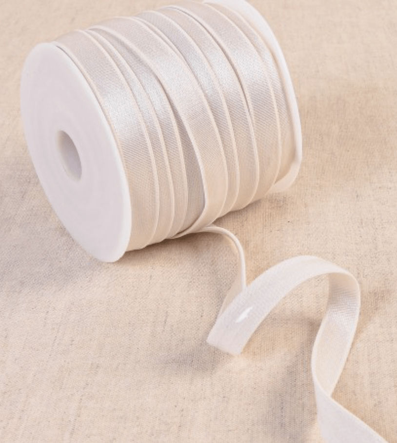 Coated elastic tape in a light color, wound on a white spool.