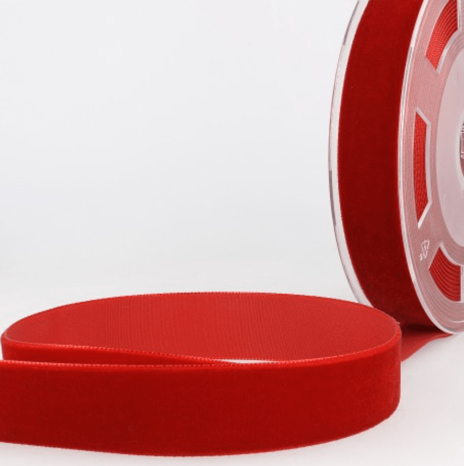 Red velvet ribbon on a spool and laid flat.