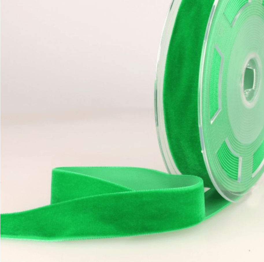 A roll of bright green velvet ribbon with a portion unwound.