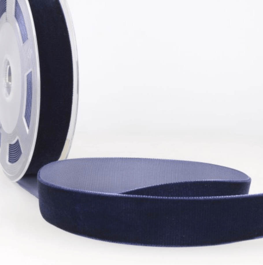 Dark blue velvet ribbon on a spool, with a portion unrolled.
