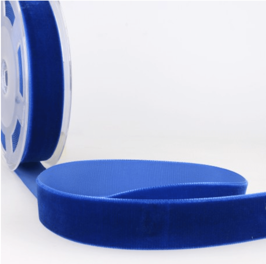 Blue velvet ribbon on a spool, with a portion unrolled.