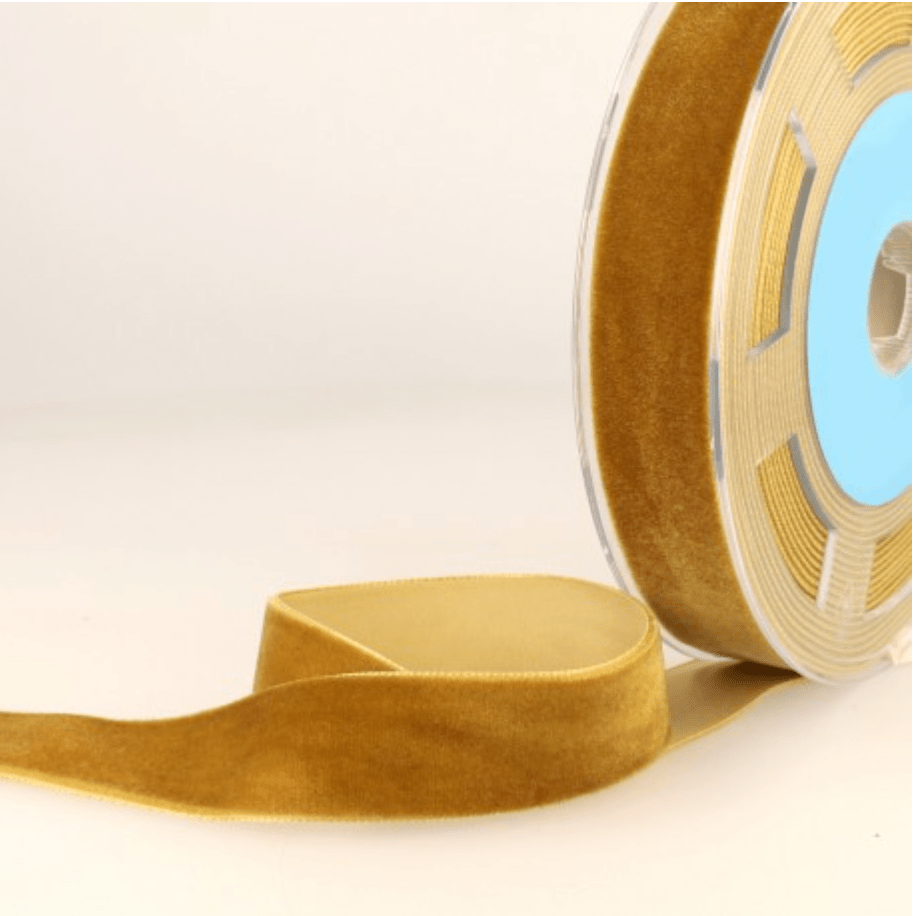 A roll of golden velvet ribbon with a loose end.