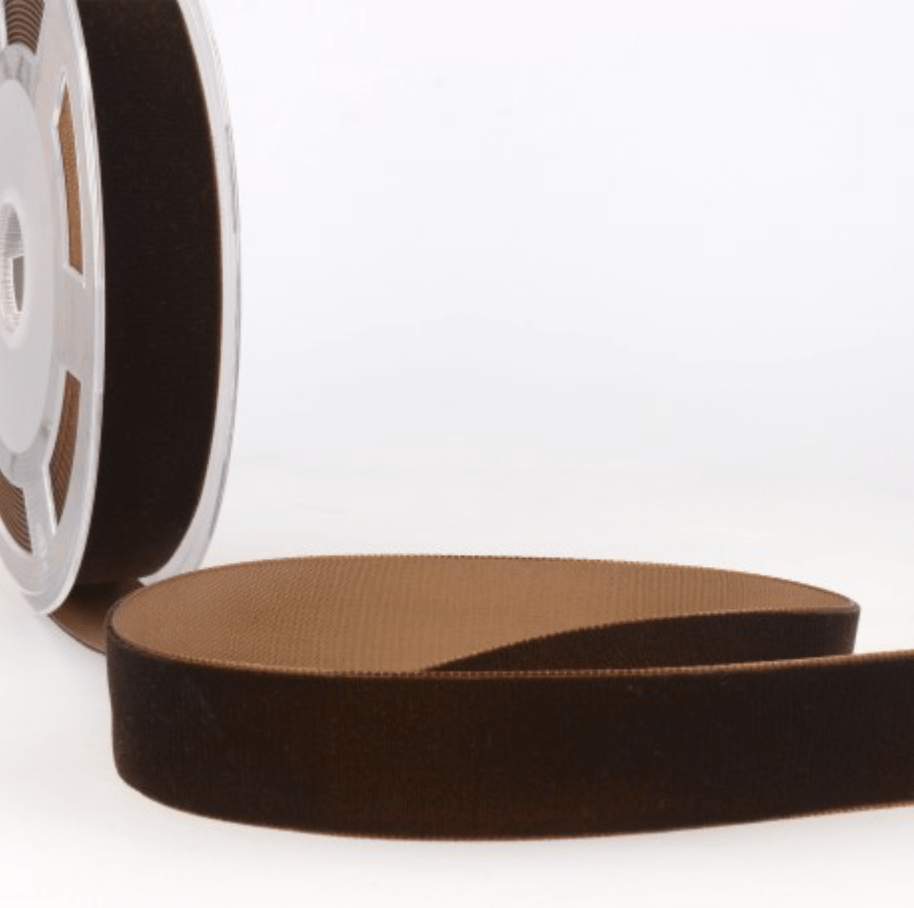 Brown velvet ribbon on a spool, with a portion unrolled.