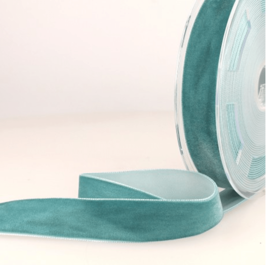 Teal velvet ribbon with white stitching on a spool.