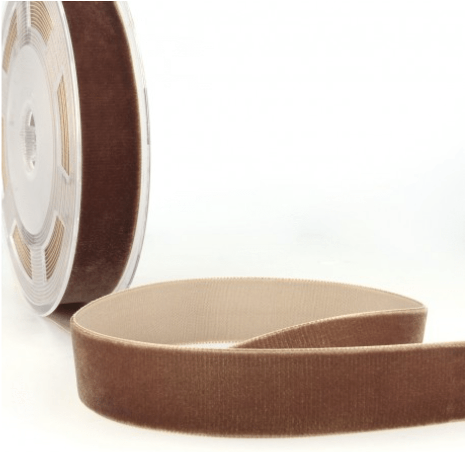 Brown velvet ribbon on a spool, with a length of ribbon unspooled.