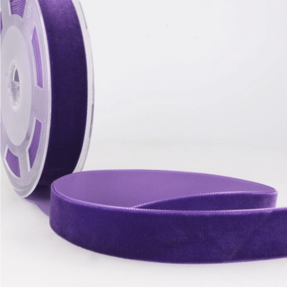 Purple velvet ribbon on a spool, with a length of ribbon unspooled.