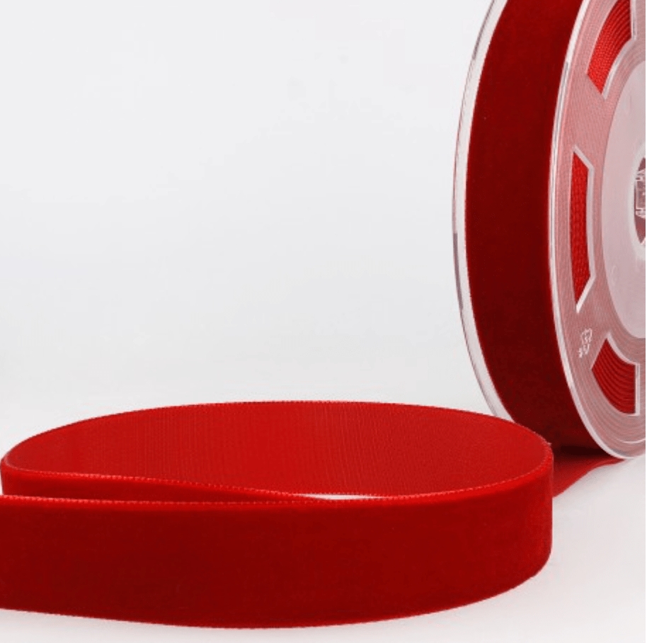 Red velvet ribbon on a spool and laid flat.