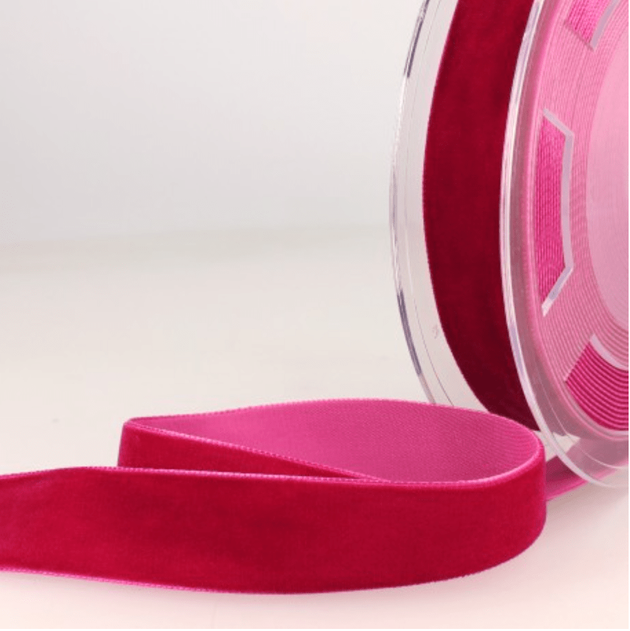 A roll of dark pink velvet ribbon with a lighter pink underside.