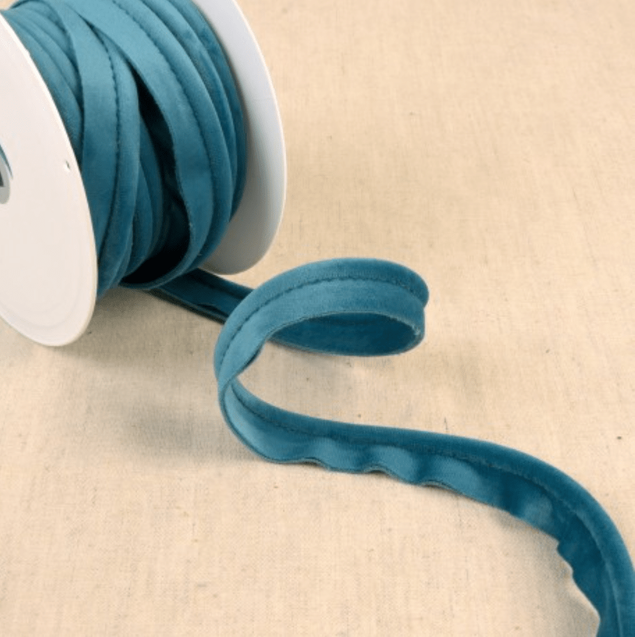 Teal velvet piping cord coiled on a white spool.