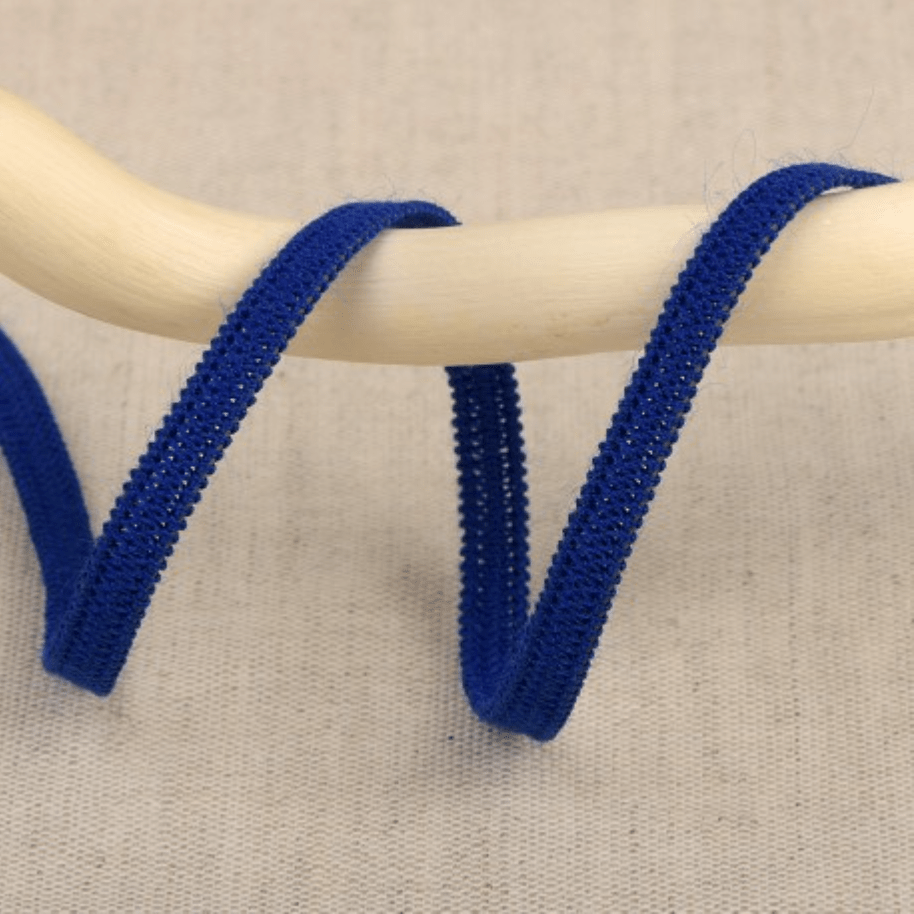 Blue elastic ribbon with a textured edge on a wooden dowel.