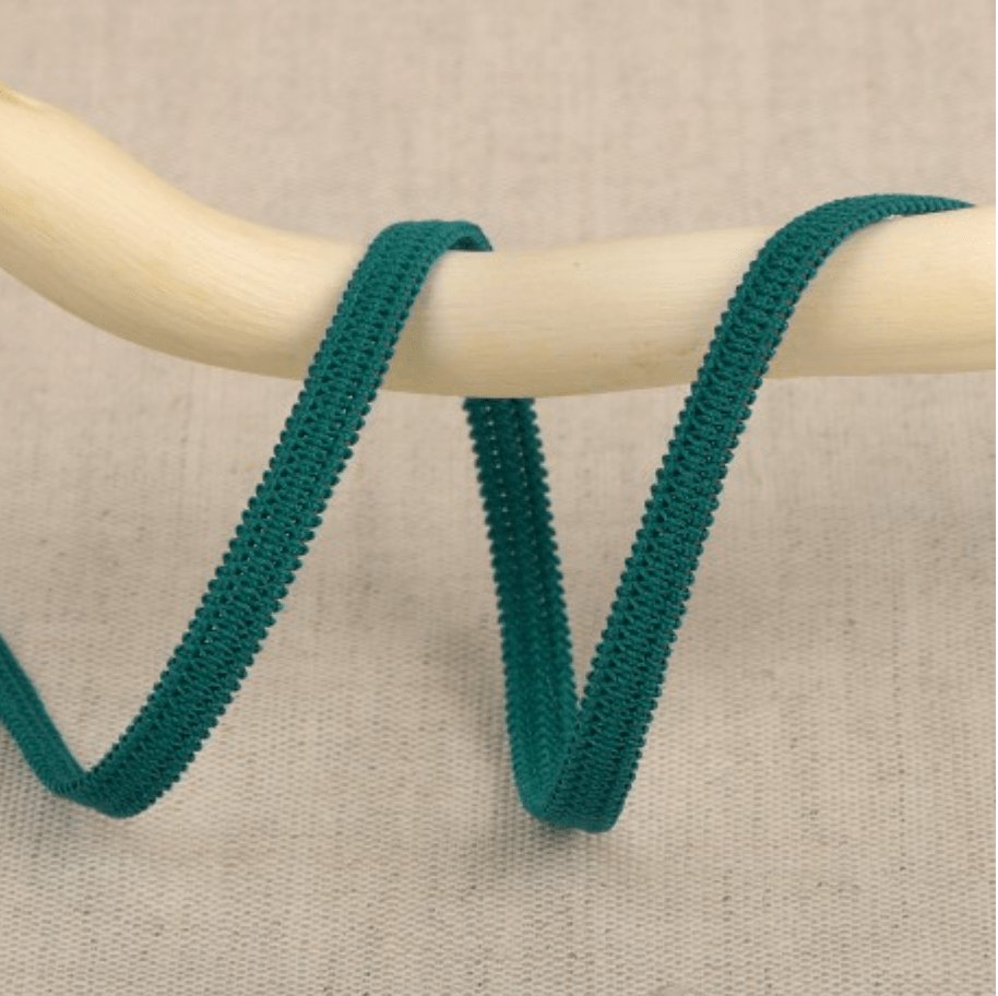 Teal elastic ribbon with a textured edge on a wooden dowel.