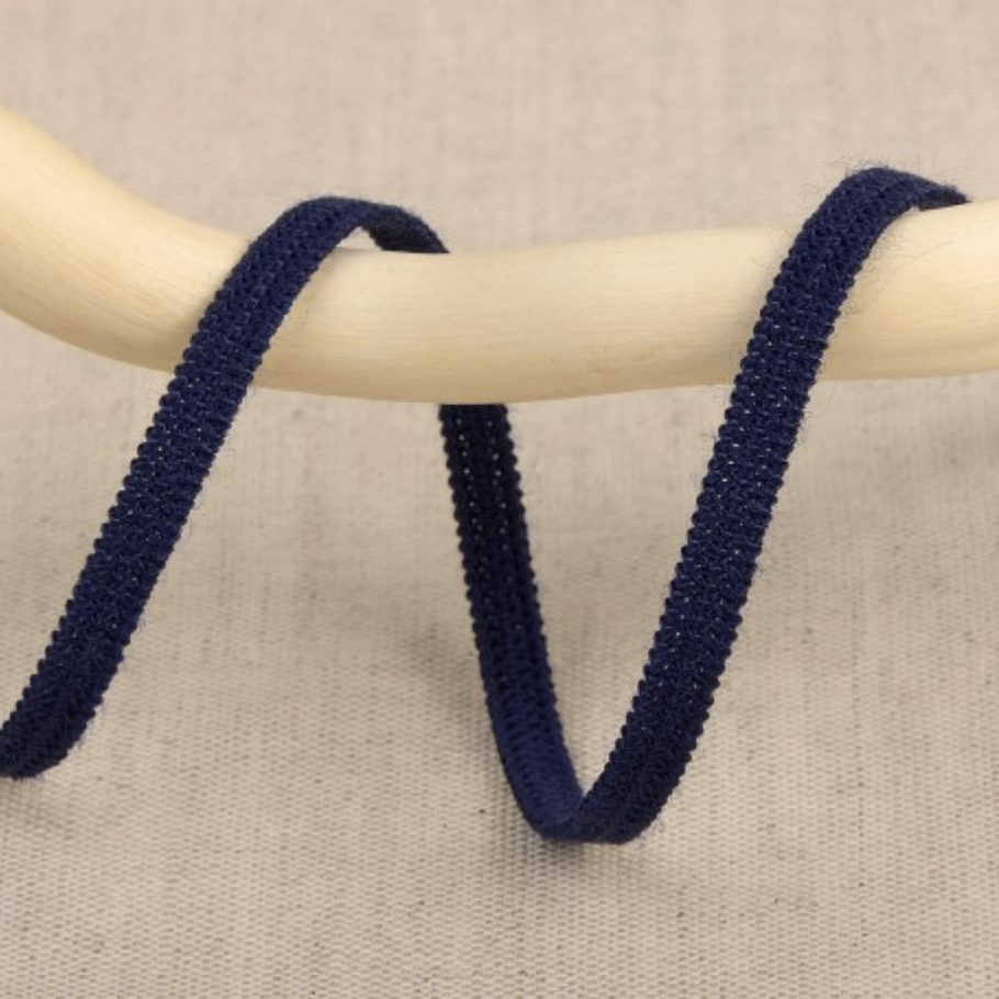 Dark blue elastic ribbon with a textured surface draped over a wooden rod.