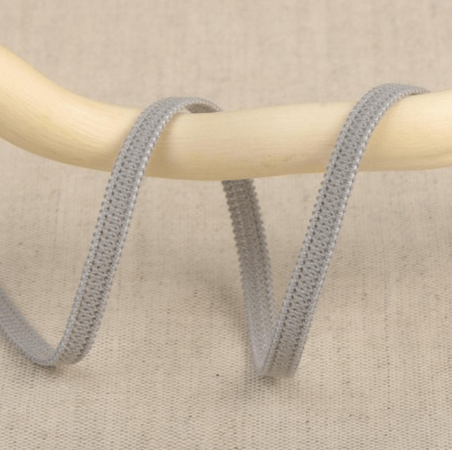 Grey elastic ribbon with a textured edge on a wooden dowel.