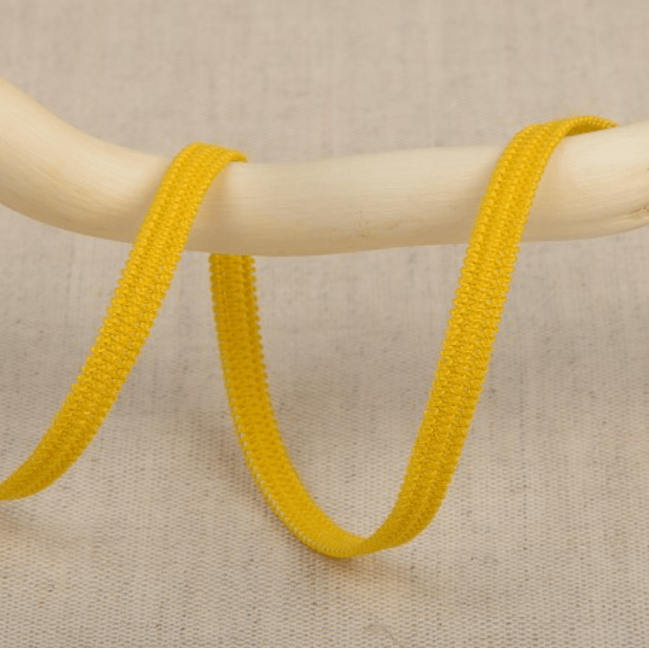 Yellow elastic ribbon with a textured surface draped over a wooden rod.