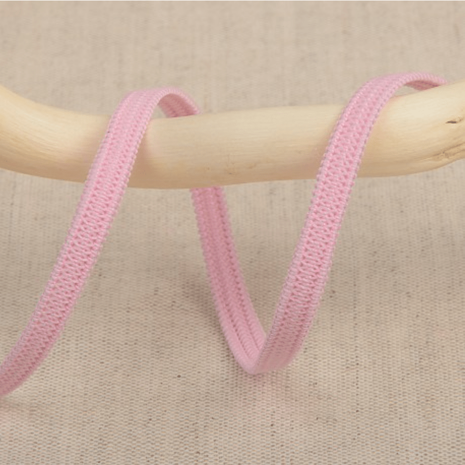 Pink elastic ribbon with a textured weave draped over a wooden rod.
