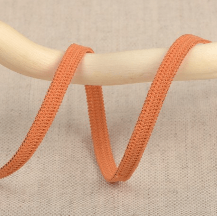 Orange elastic ribbon with a textured weave on a wooden dowel.