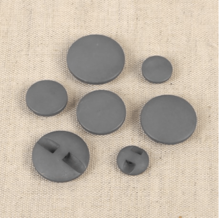 Set of seven grey polyester buttons of various sizes, some with two holes.