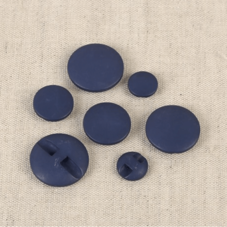 Set of seven dark blue polyester buttons of varying sizes on a textured fabric background.