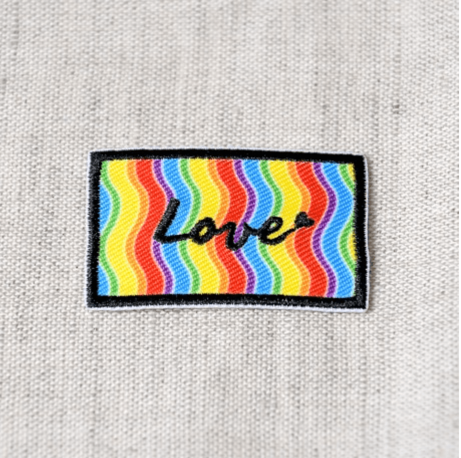 Rectangular patch with rainbow wavy stripes and the word "Love" embroidered in black.