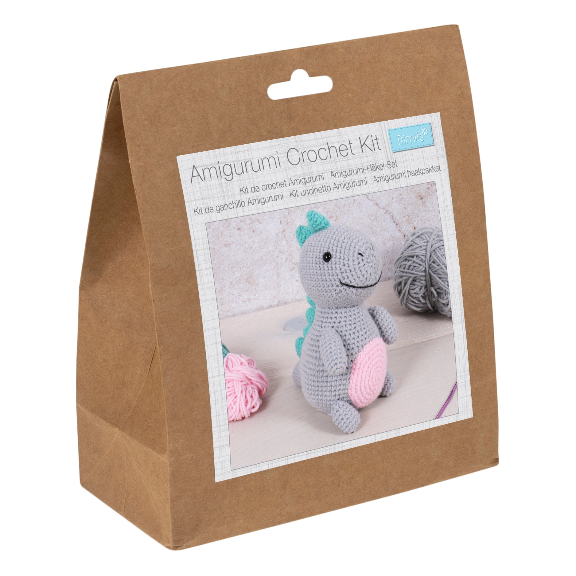 Amigurumi crochet kit for a grey dinosaur with a pink belly and teal spikes in a brown paper bag.