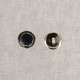 Two Stephanoise enamelled metal buttons, one black and one silver, on a textured background.