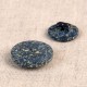 Two round, dark blue buttons with a speckled texture made from rice husk and polyester.