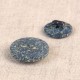 Two round, dark grey buttons with a speckled texture made from rice husk and polyester.