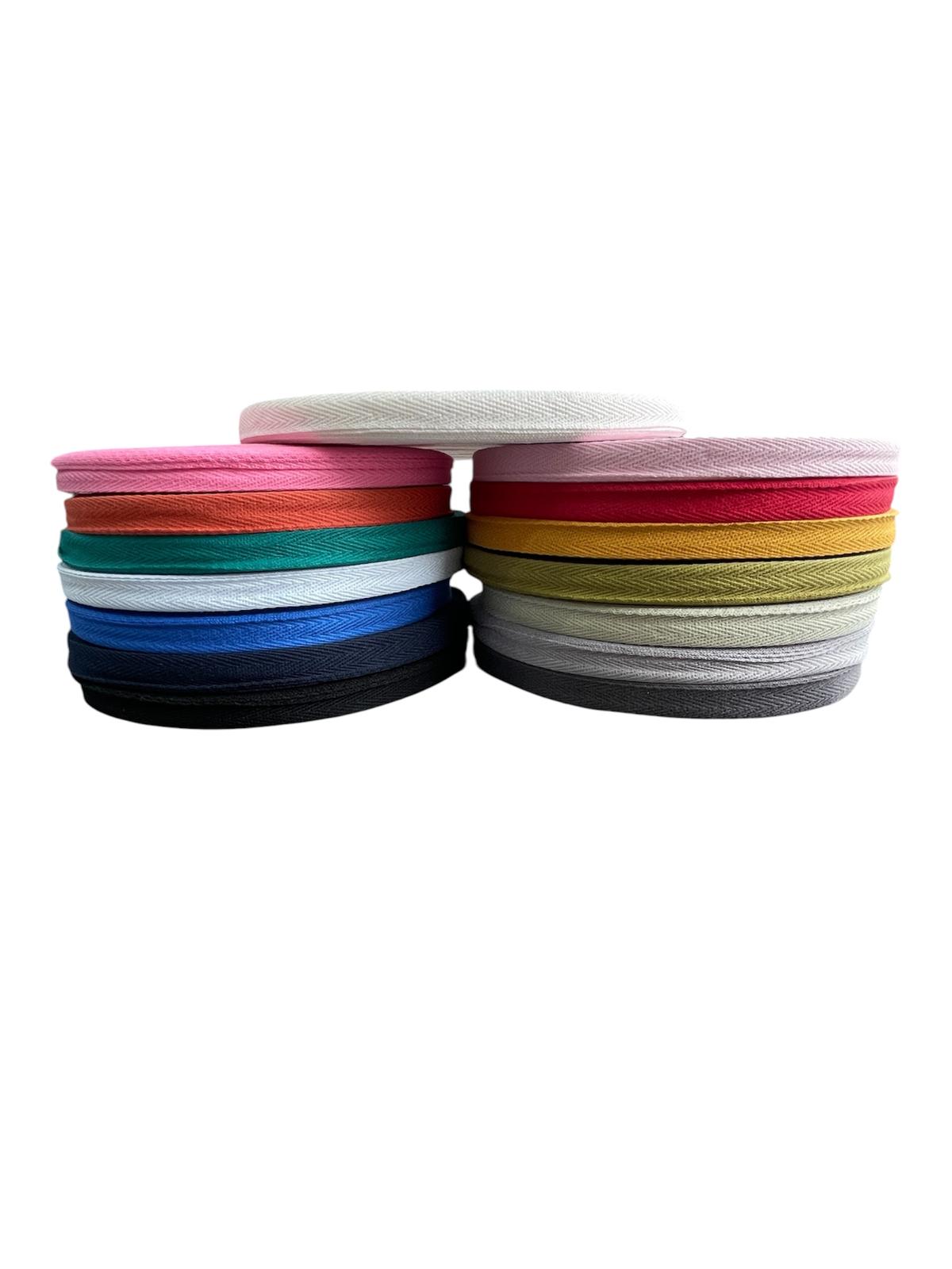 Herringbone cotton twill webbing tape in various colors stacked in two piles on a white background.