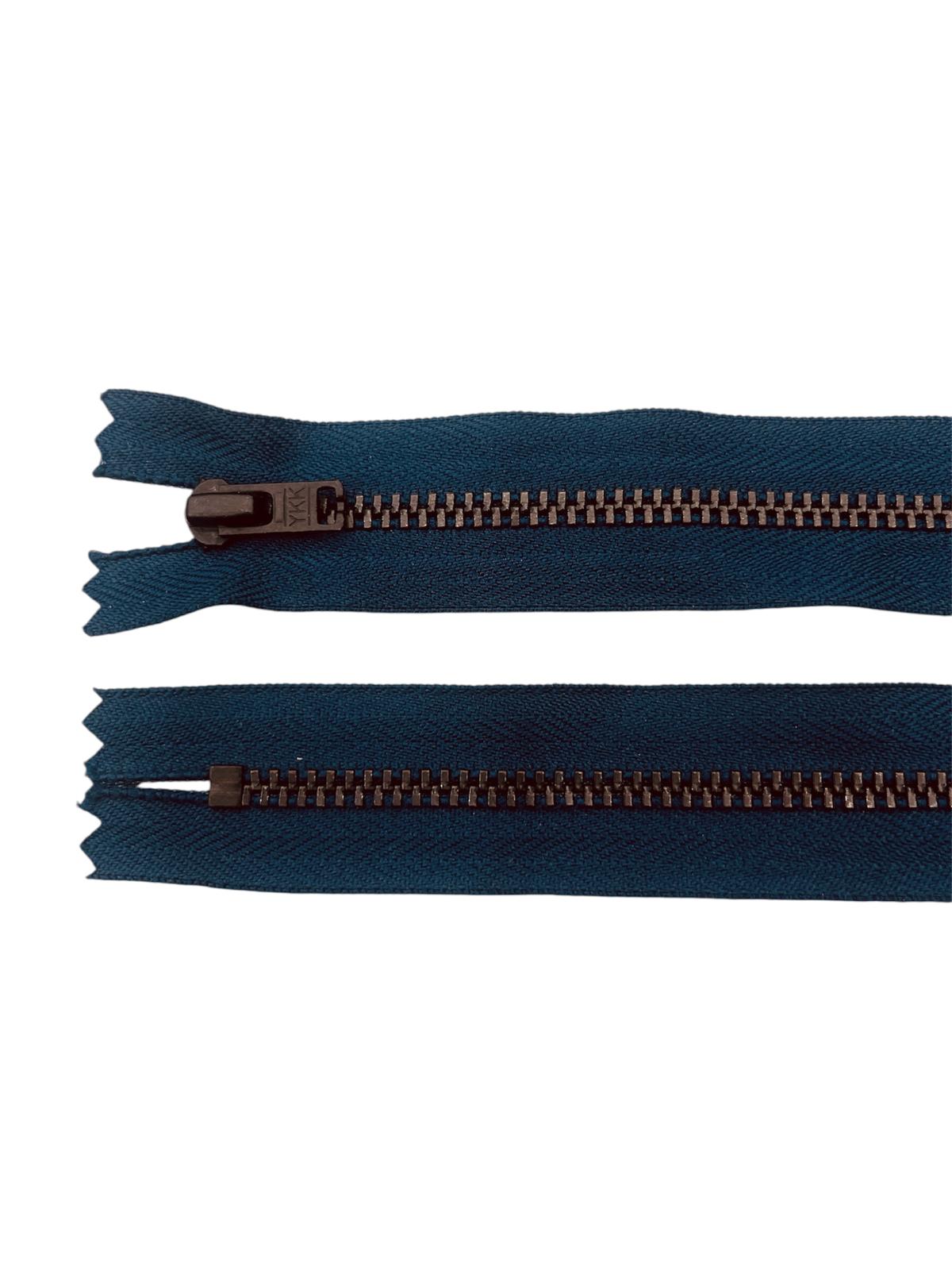 Two dark teal zippers with black metal teeth, one with a black slider.