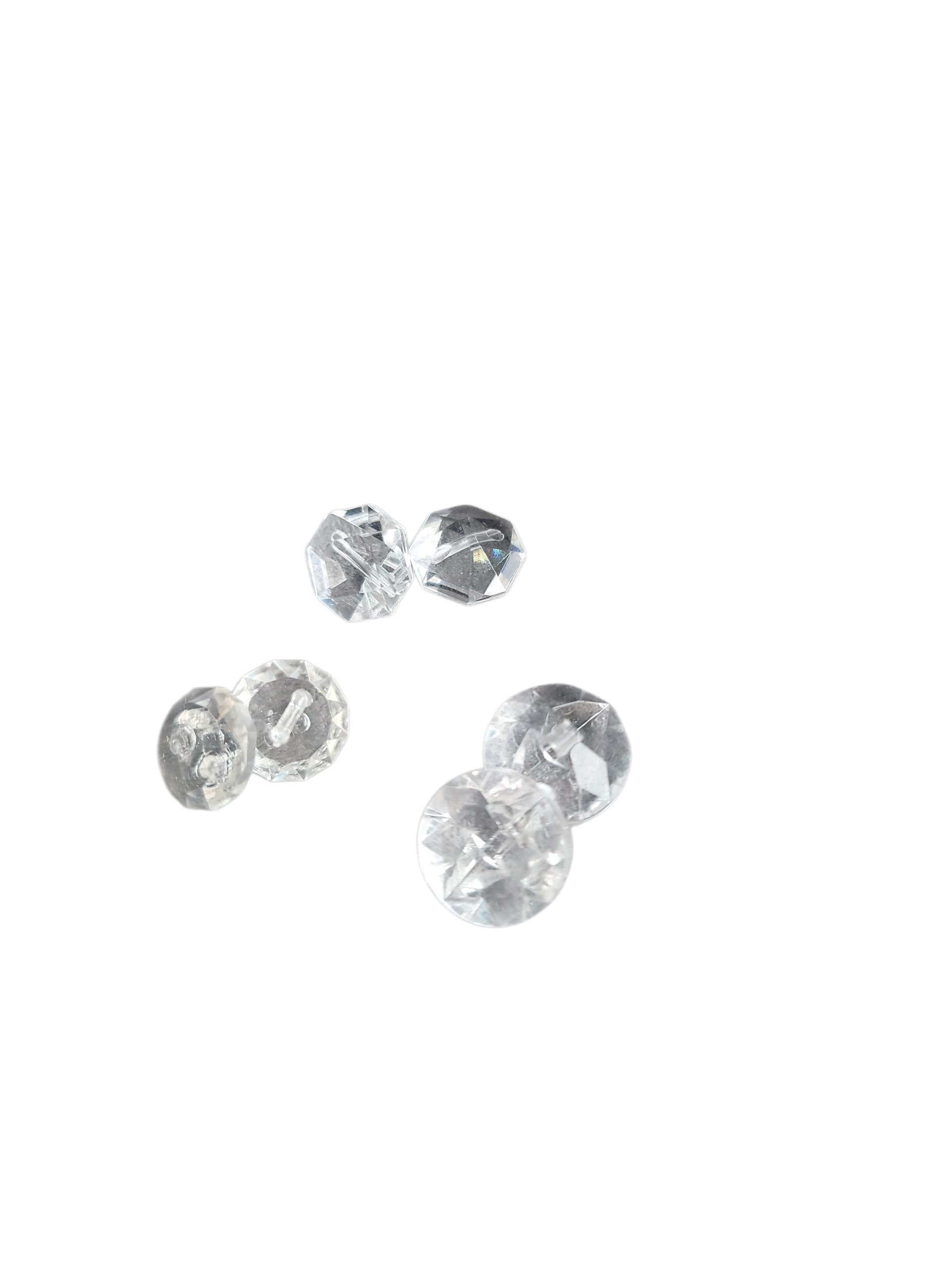 Six clear, diamond-faceted shank buttons in various sizes are scattered on a white background.