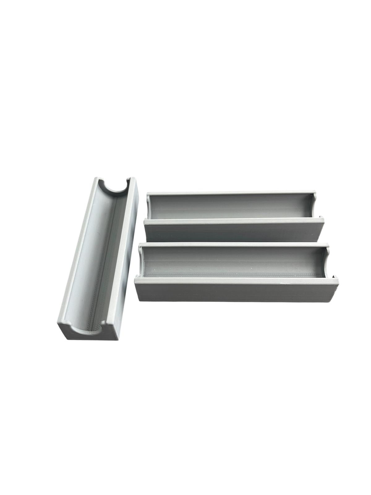 Grey plastic bobbin case organizer for sewing tools, measuring 10cm by 2.8cm.