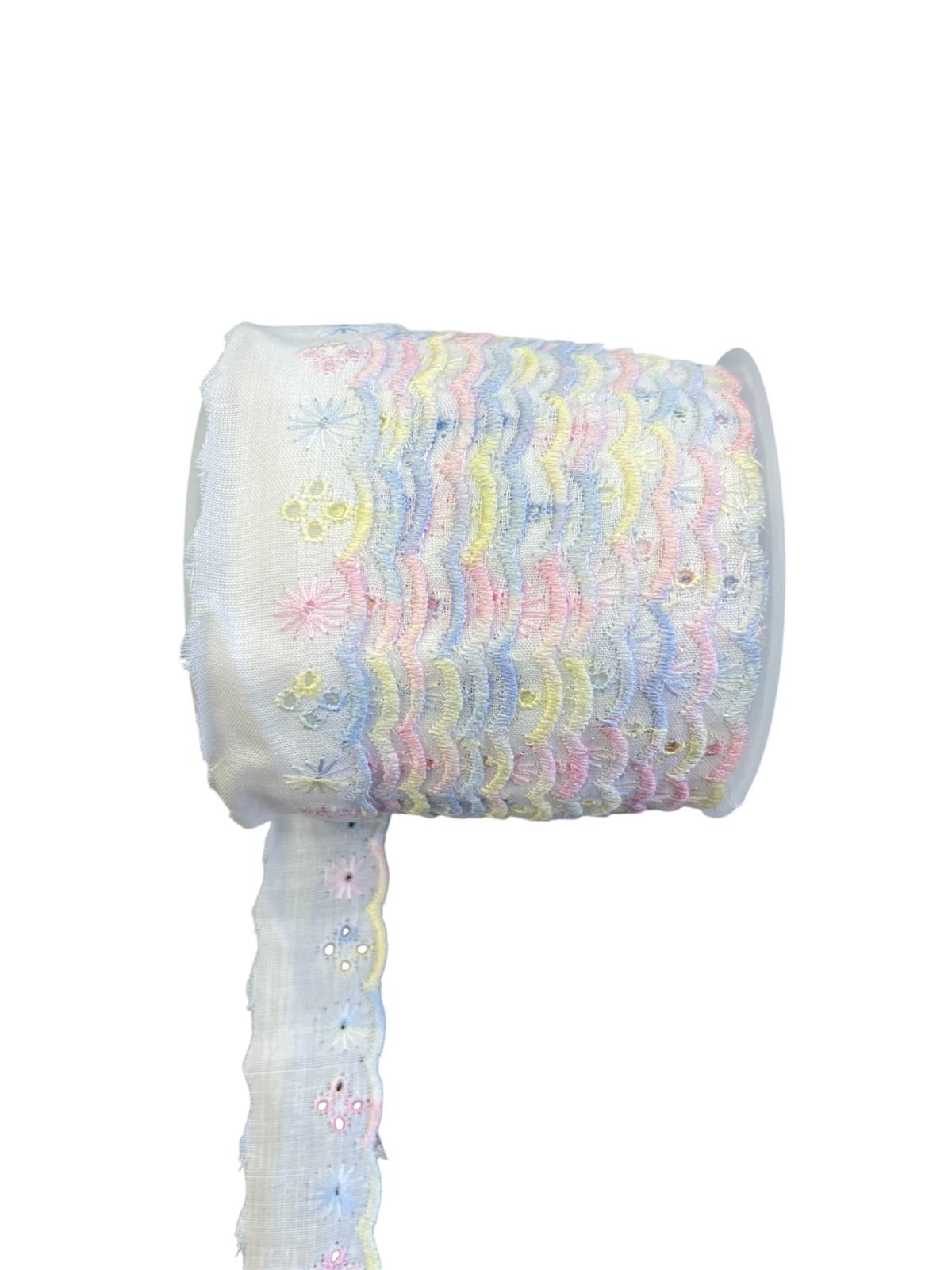 A roll of white cotton trim featuring pastel rainbow scalloped edges and embroidered floral details.