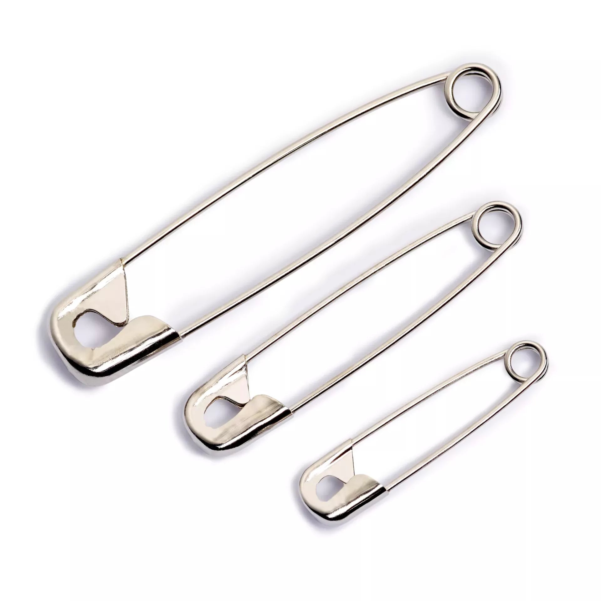 Three silver-coloured steel safety pins in varying sizes on a white background.