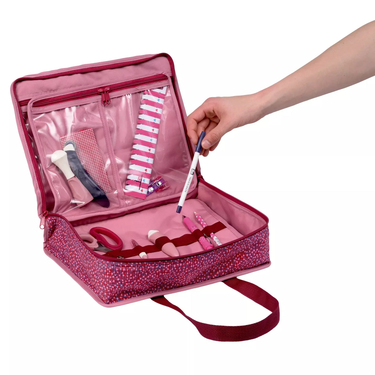 Open burgundy all-in-one craft bag with transparent pockets and loops holding sewing accessories.