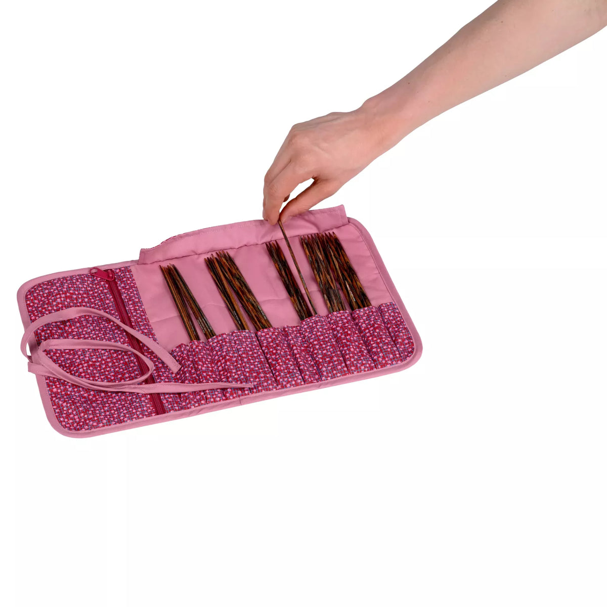 Burgundy patterned cotton needle case with ten compartments holding wooden knitting needles.