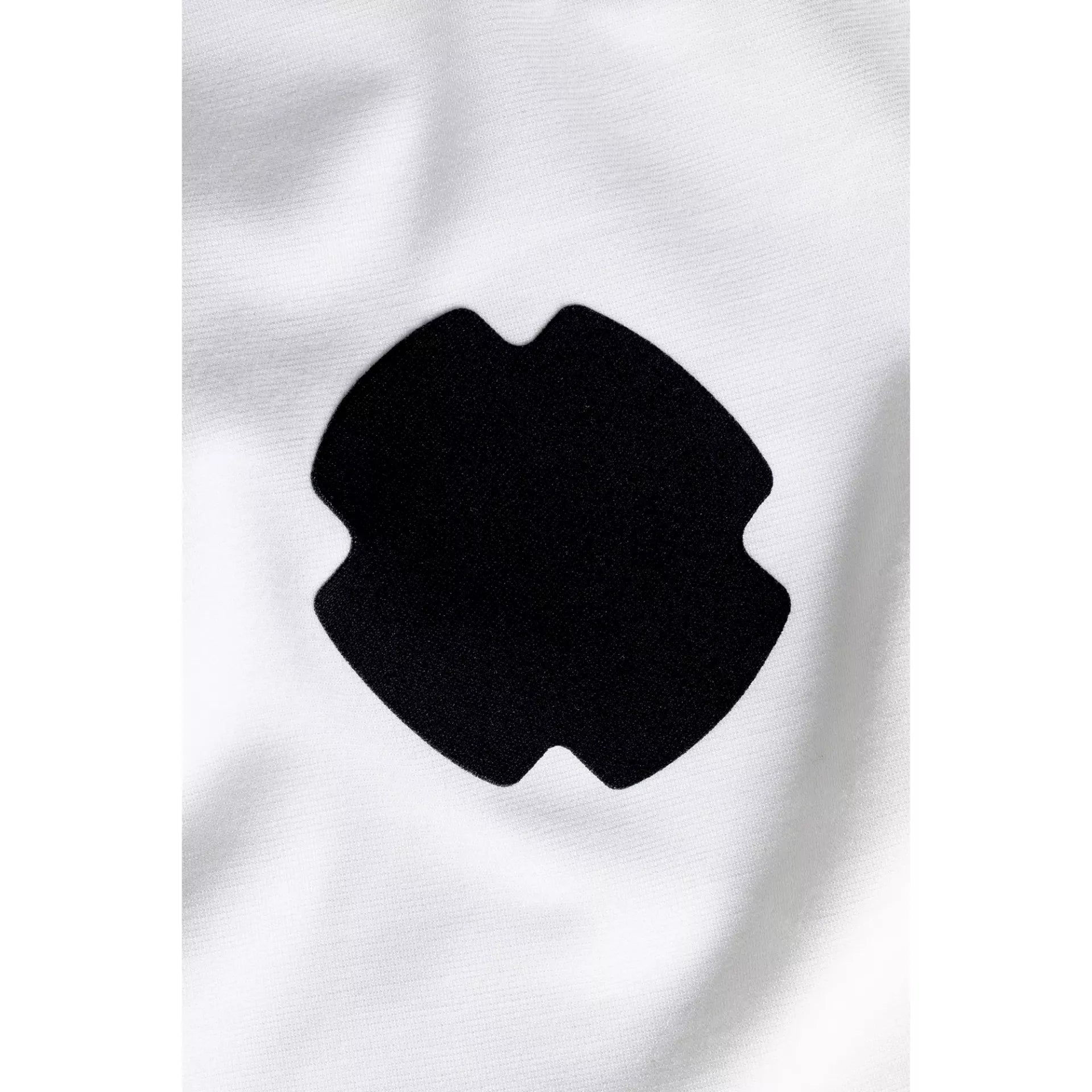 Close-up of a black, cross-shaped rub-on textile repair patch on white fabric.