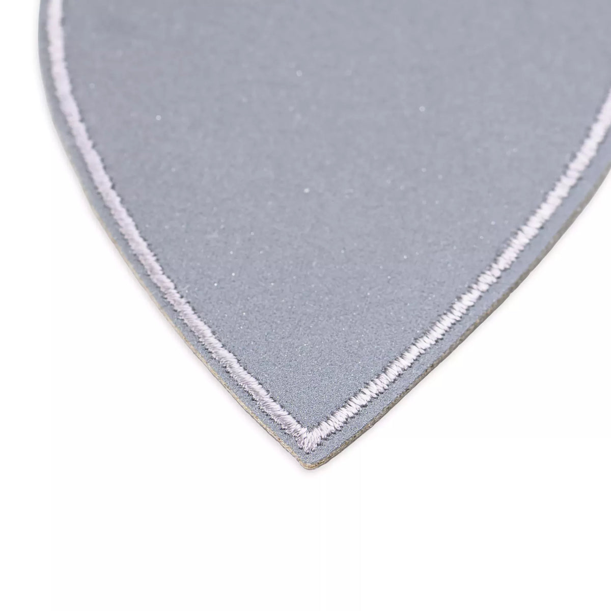 Close-up of a grey reflective heart-shaped appliqué with white stitched border.