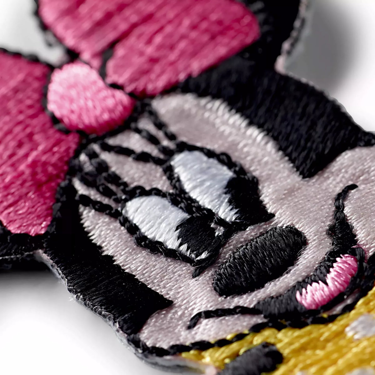 Close-up of a Minnie Mouse embroidered iron-on appliqué with a pink bow and yellow dress.