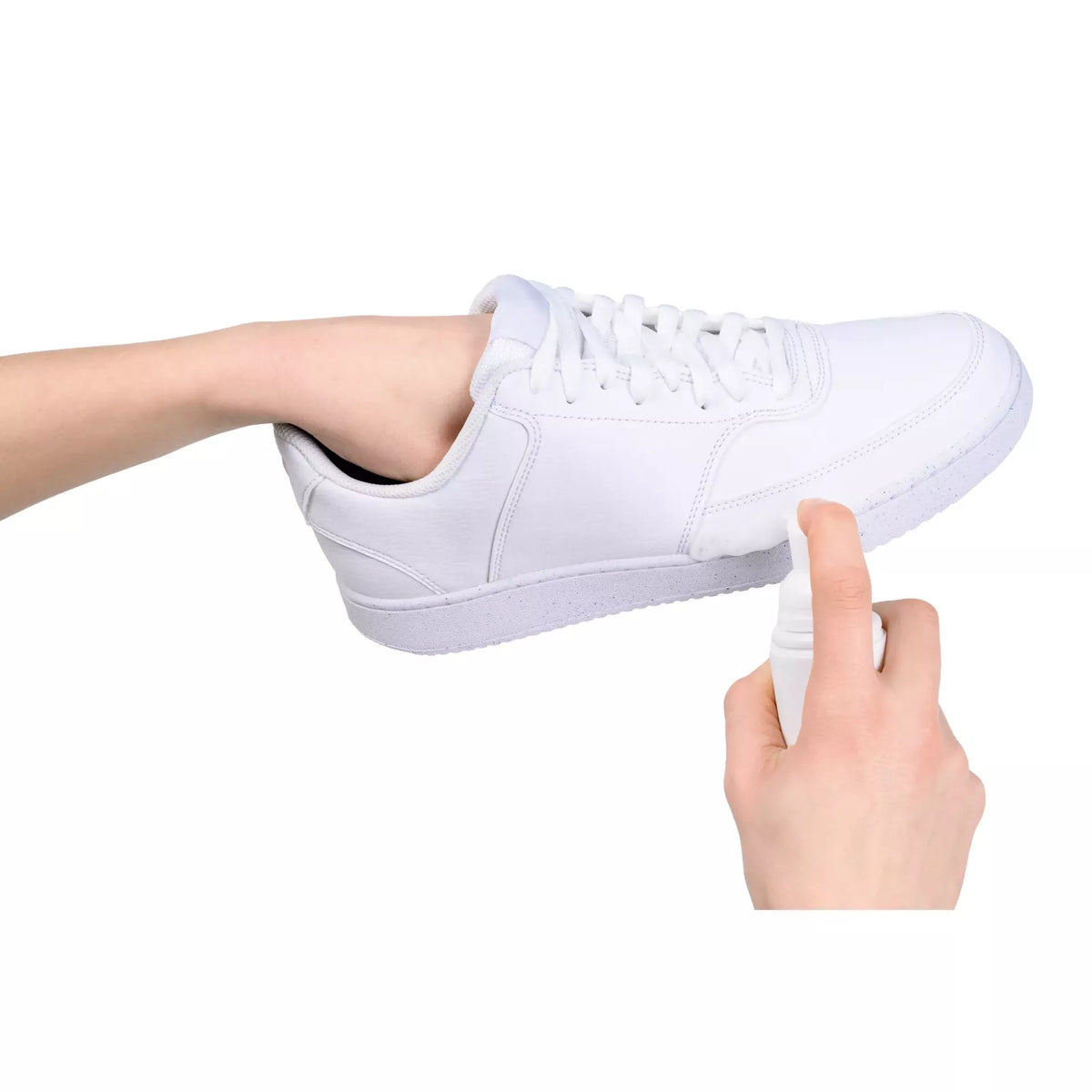 Person applying cleaning foam from a spray bottle onto a white sneaker.
