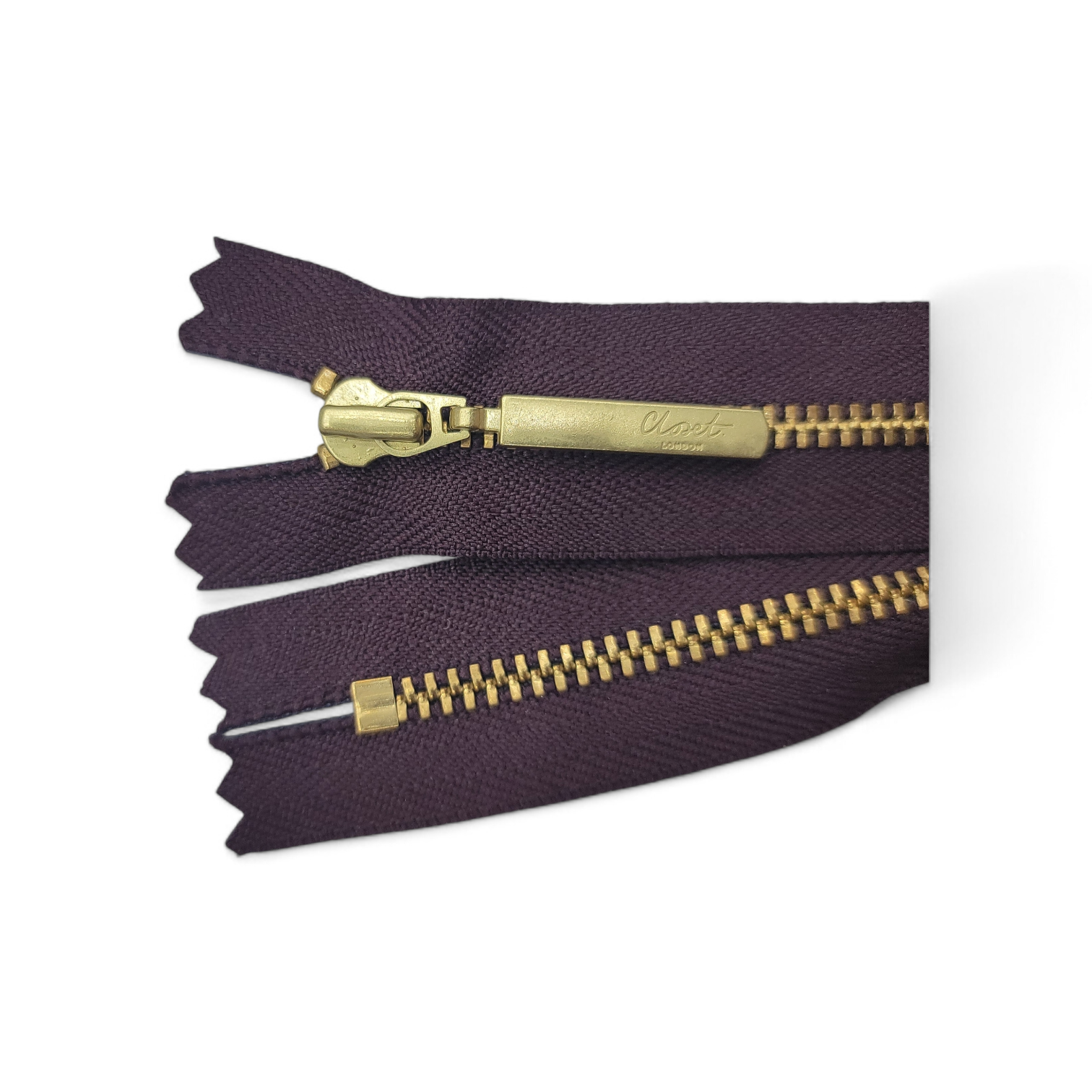 YKK size 3 closed end gold metal zip on dark purple fabric.