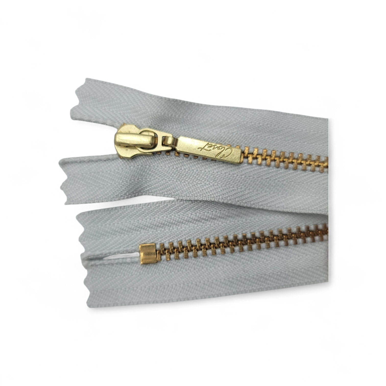 YKK size 3 closed end gold metal zipper with grey fabric.