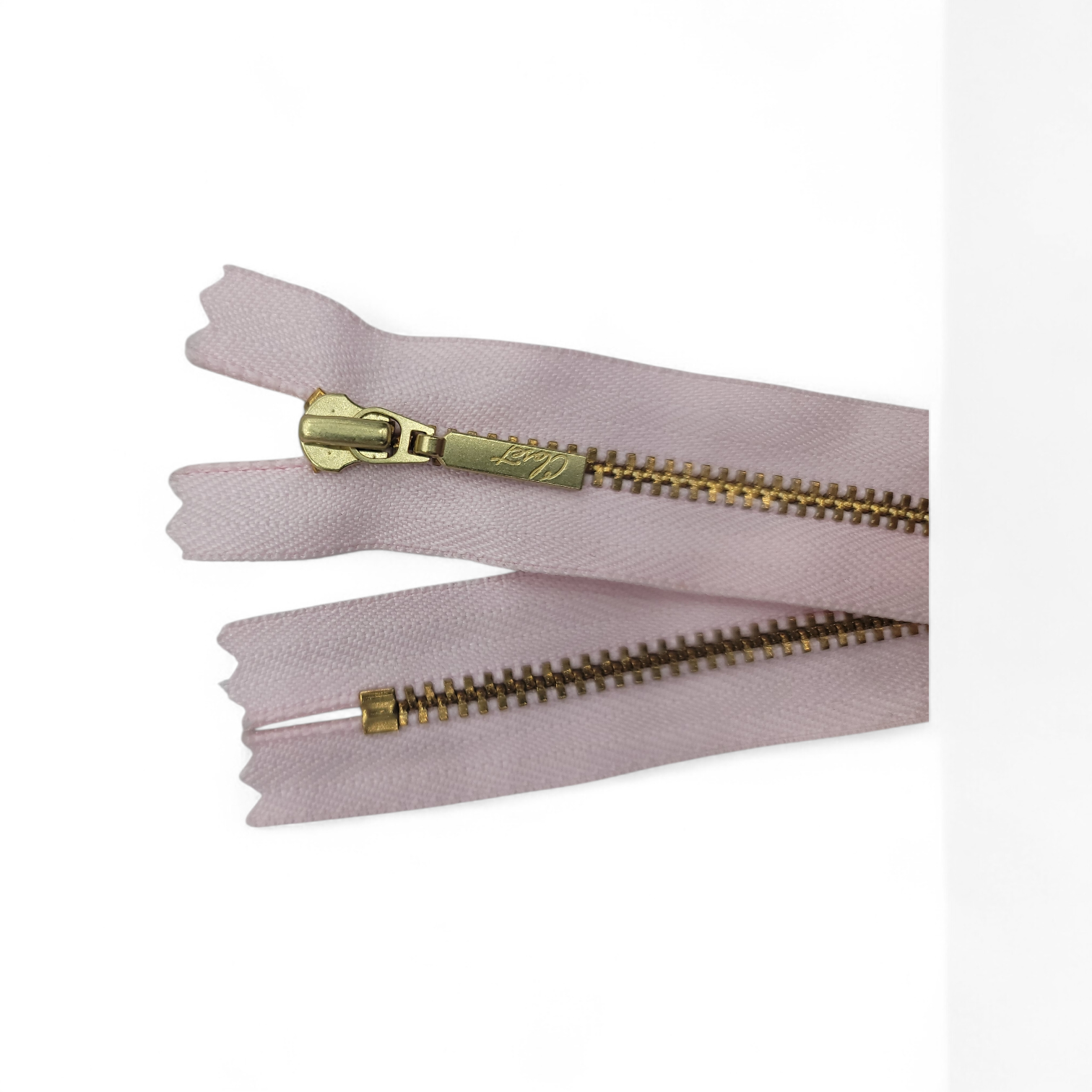 YKK size 3 closed end gold metal zipper on pink fabric.