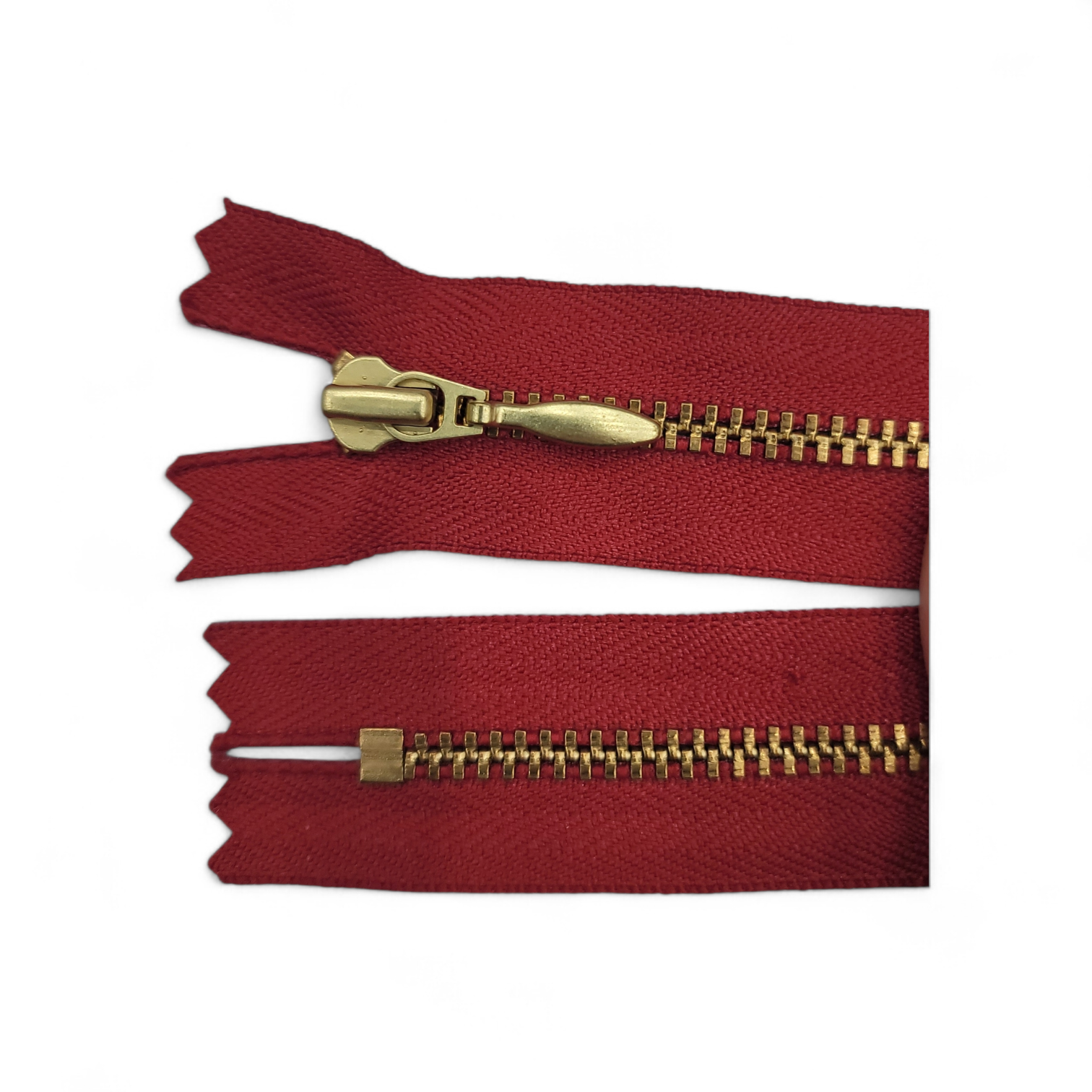 YKK size 3 closed end gold metal zipper on red fabric.
