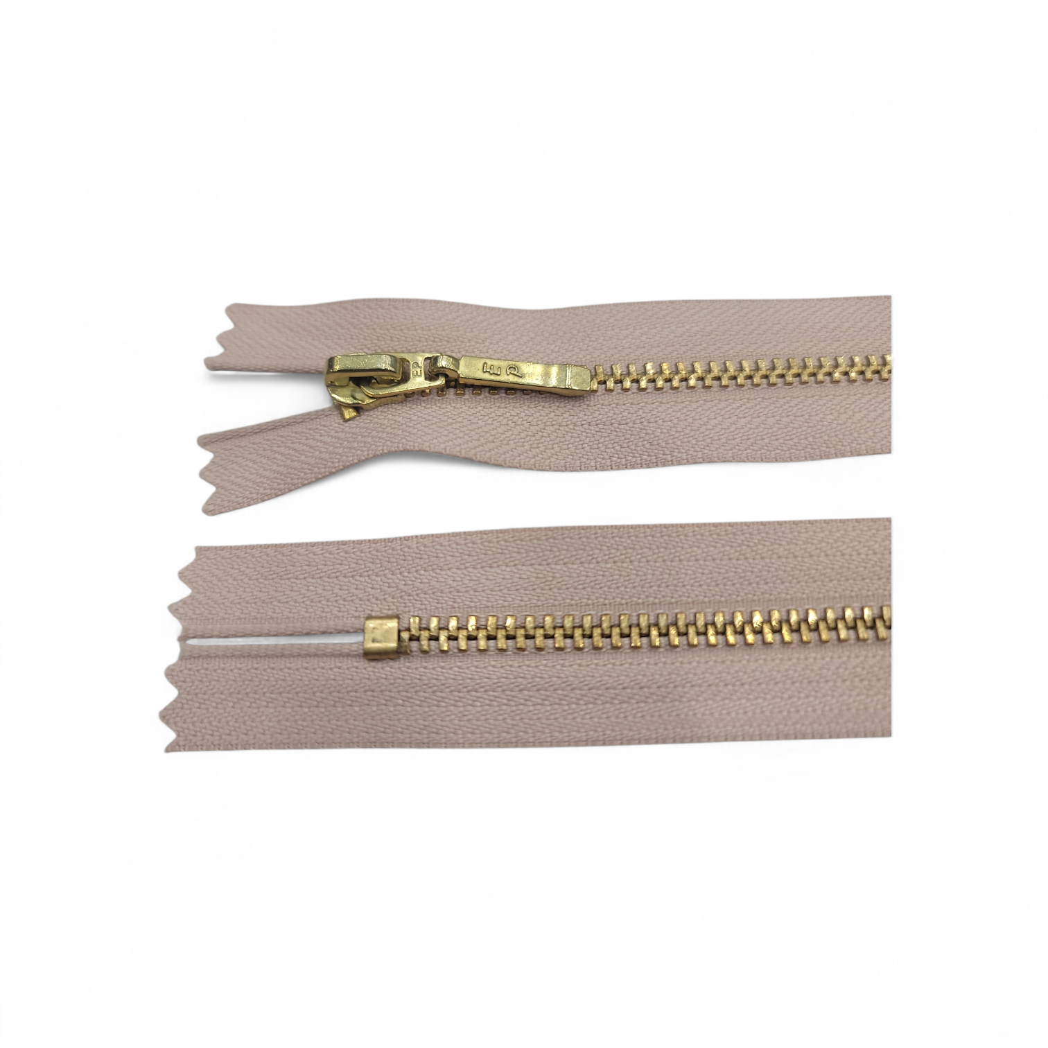YKK size 3 closed end gold metal zipper on beige fabric.